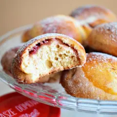 Puszyste pączki z piekarnika z nadzieniem z dżemu, posypane cukrem pudrem, kuszą swoim domowym wyglądem.