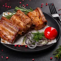 Soczyste żeberka z grilla, podane z pomidorkiem, cebulką i ziołami. Idealne na letnie wieczory.