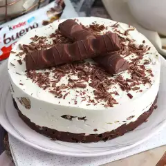 Pyszny sernik Kinder Bueno, udekorowany kawałkami batoników i czekoladową posypką. Idealny deser dla fanów słodkości.