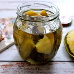 Słoik z ogórkami i ananasem, obok czosnek i plasterki ananasa. Nietypowe połączenie smaków.
