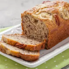 Pyszny chlebek bananowy z orzechami pekan i plasterkami banana na wierzchu, pokrojony na kromki.