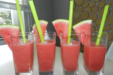 Cztery szklanki orzeźwiającej lemoniady arbuzowej z plasterkami arbuza i zielonymi słomkami. Idealne na upalne dni, pokazują, jak zrobić lemoniadę arbuzową.