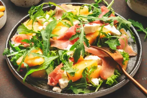 Orzeźwiająca sałatka z melonem, rukolą, mozzarellą i szynką parmeńską. Idealna na letnie dni.