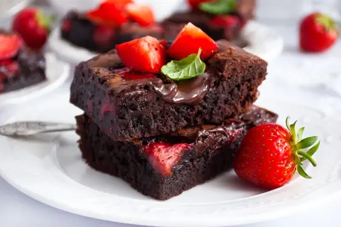 Pyszne brownie z truskawkami, polane czekoladą i ozdobione świeżymi owocami. Idealne na deser.