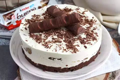 Pyszny sernik Kinder Bueno, udekorowany kawałkami batoników i czekoladową posypką. Idealny deser dla fanów słodkości.