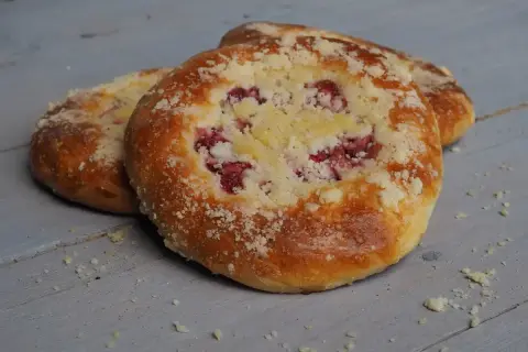 Pyszna drożdżówka z kruszonką i malinami, pachnąca domowym ciepłem.