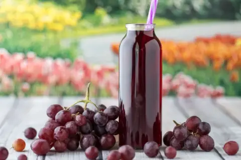 Butelka z sokiem z winogron i kiście świeżych owoców. Idealne na lato, gdy zastanawiasz się, co zrobić z winogron.