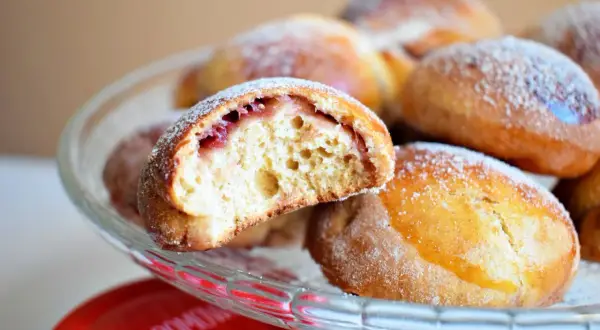 Puszyste pączki z piekarnika z nadzieniem z dżemu, posypane cukrem pudrem, kuszą swoim domowym wyglądem.
