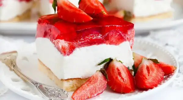 Pyszny biszkopt z truskawkami i mascarpone, oblany galaretką. Idealny deser na letnie popołudnie.