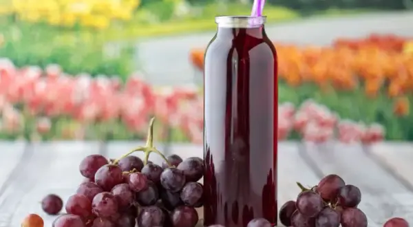 Butelka z sokiem z winogron i kiście świeżych owoców. Idealne na lato, gdy zastanawiasz się, co zrobić z winogron.