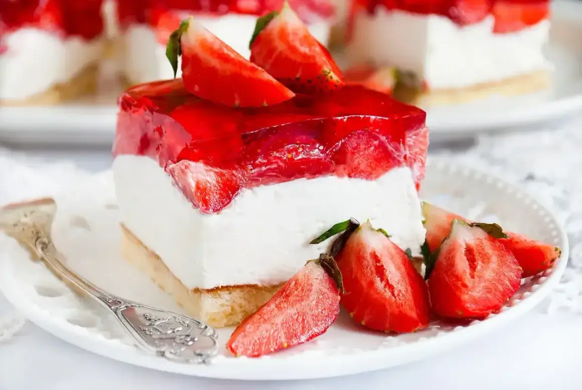Pyszny biszkopt z truskawkami i mascarpone, oblany galaretką. Idealny deser na letnie popołudnie.