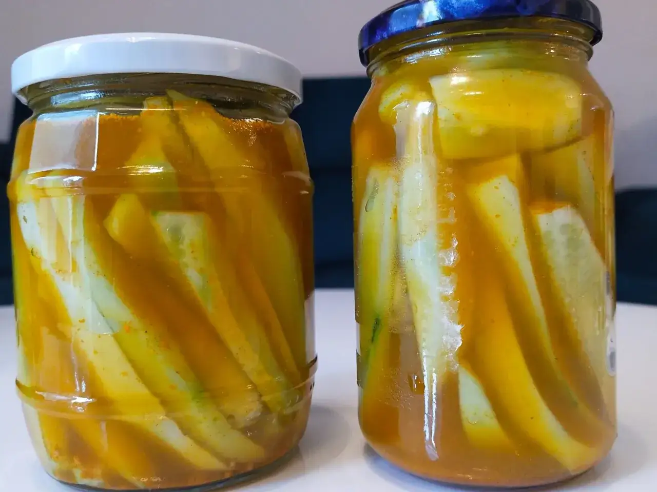Dwa słoiki z ogórkami w zalewie curry, gotowe do przechowywania. Przepisy Joli na pikantne przetwory.