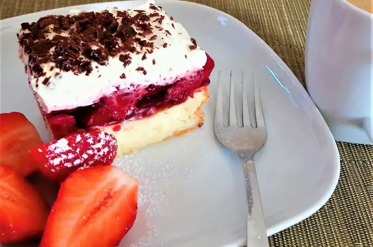 Pyszny biszkopt z truskawkami i mascarpone, posypany wiórkami czekolady, z dodatkiem świeżych truskawek.