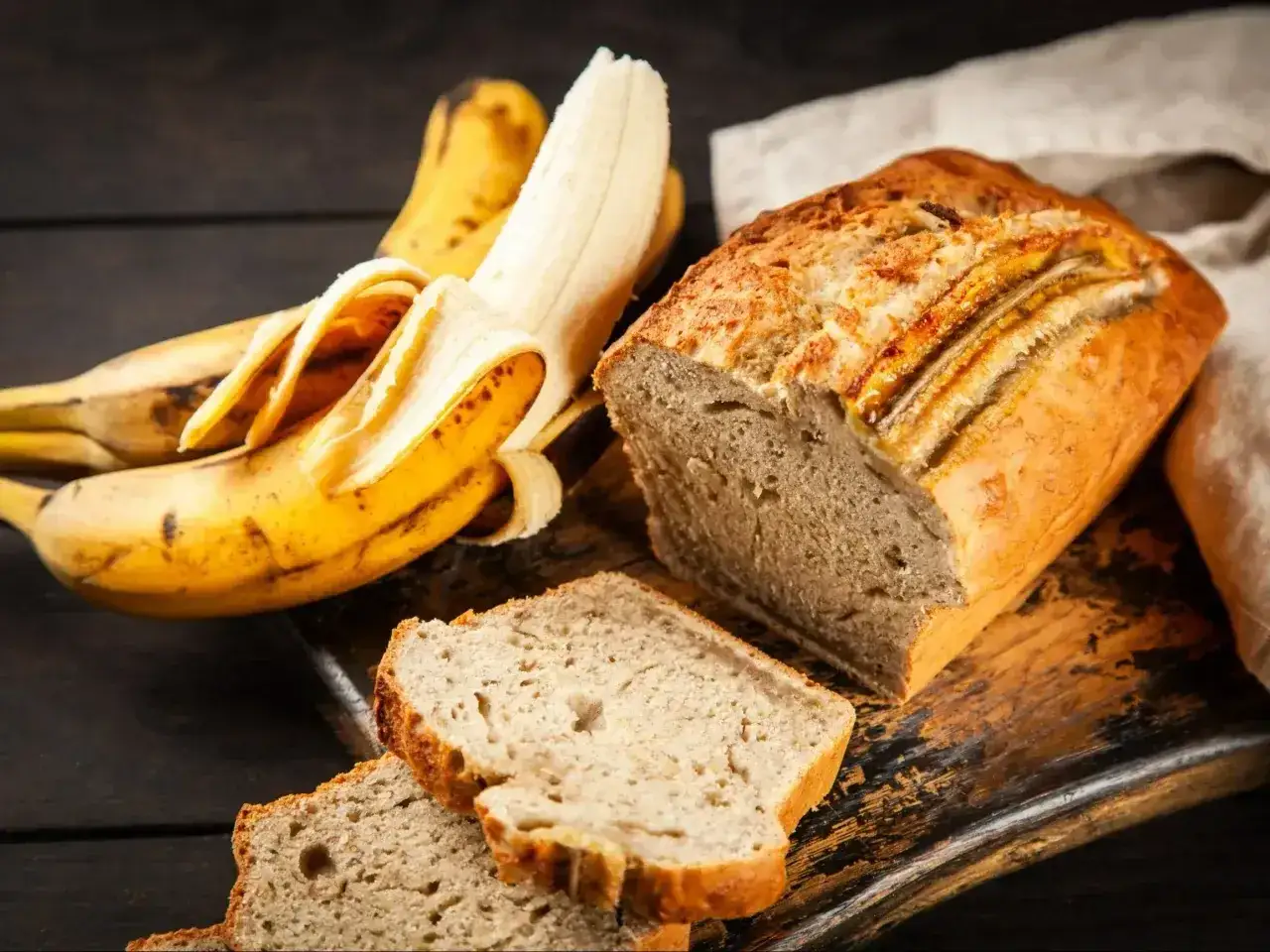 Pyszny chlebek bananowy fit, idealny na zdrowe śniadanie. Obok leżą dojrzałe banany, gotowe do upieczenia.