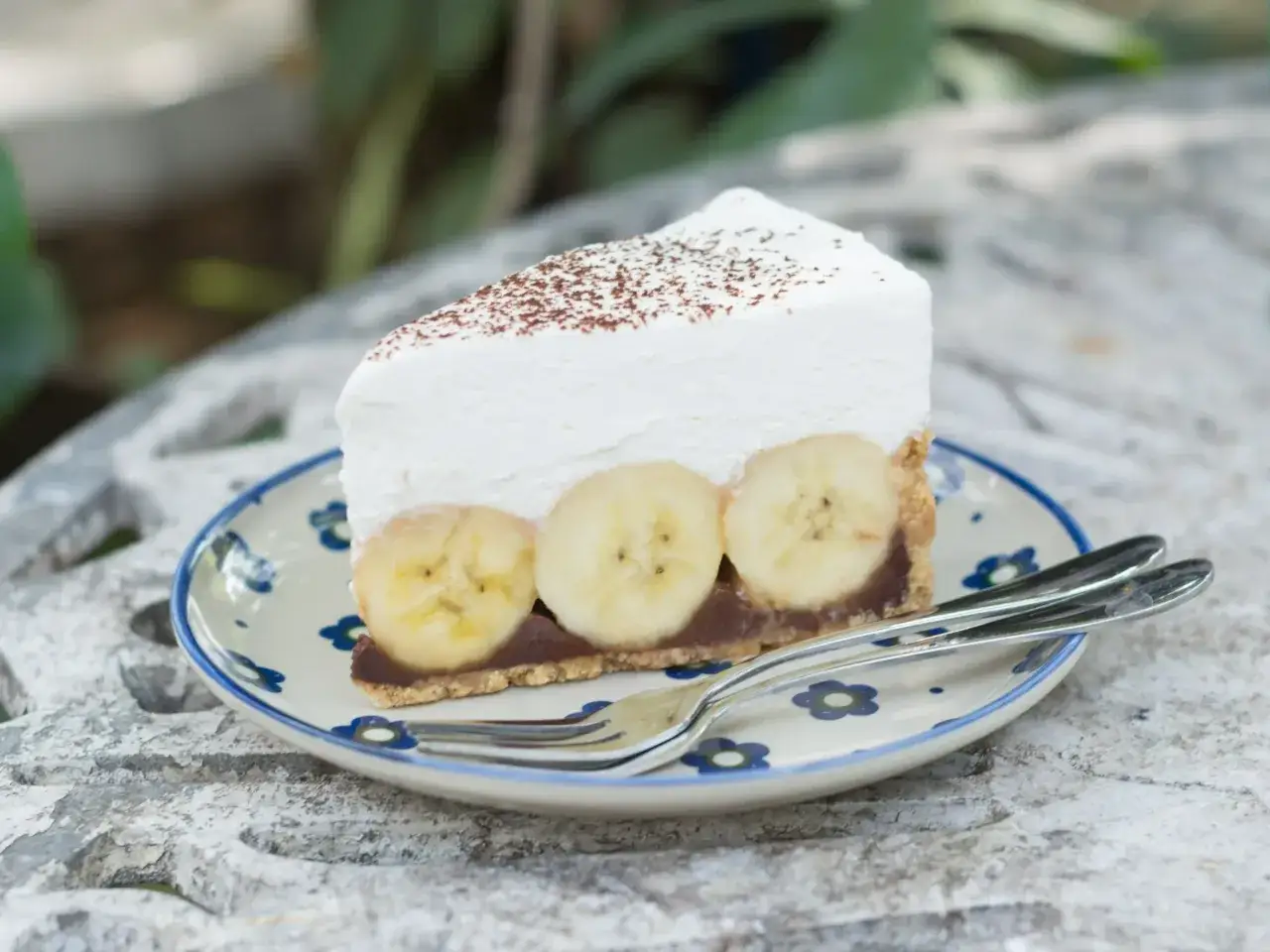 Pyszne ciasto bananowe bez pieczenia z kremem i bananami, posypane kakao. Idealne na deser.