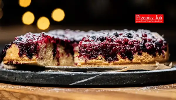 Pyszne ciasto z porzeczkami, posypane cukrem pudrem, prezentuje się apetycznie na kamiennej tacy.