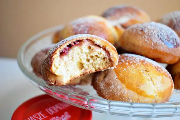 Puszyste pączki z piekarnika z nadzieniem z dżemu, posypane cukrem pudrem, kuszą swoim domowym wyglądem.