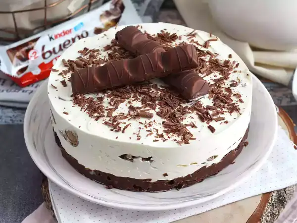 Pyszny sernik Kinder Bueno, udekorowany kawałkami batoników i czekoladową posypką. Idealny deser dla fanów słodkości.