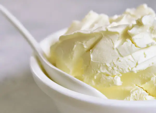 Kremowa masa w białej miseczce z łyżką. Szukasz, czym zastąpić mascarpone? Oto puszysta alternatywa.